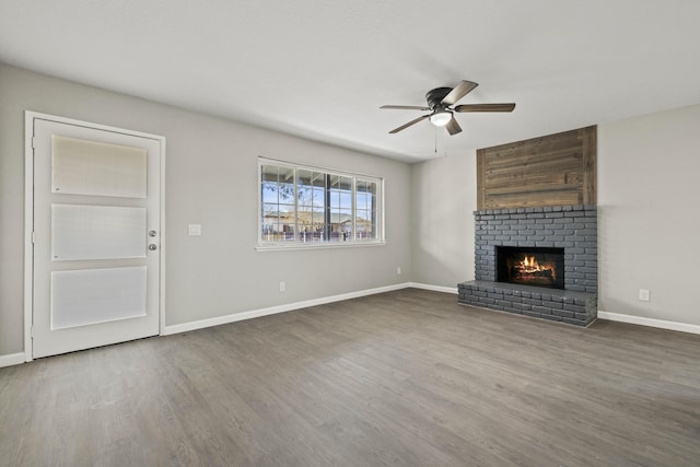 unfurnished living room featuring hardwood / wood-style floors, a brick fireplace, and ceiling fan