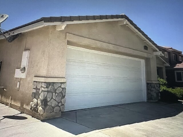 45559 Robinson Dr, Lancaster, CA 93535 - view of home's exterior featuring stone siding, a garage, stucco siding, and concrete driveway