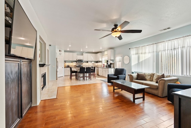 living room featuring ceiling fan and a tile fireplace