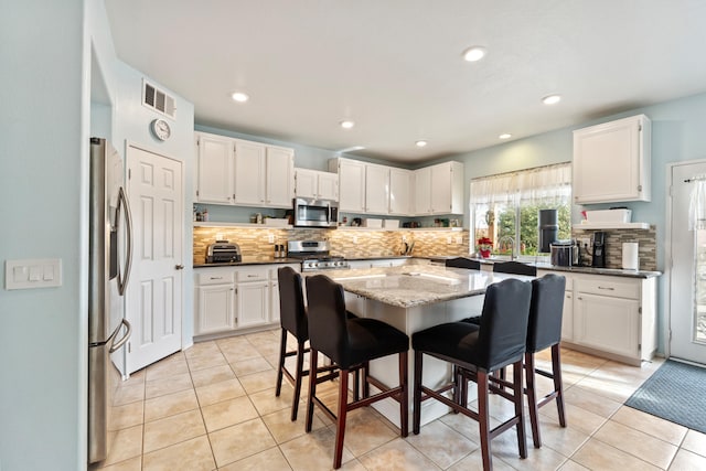 kitchen with tasteful backsplash, light tile patterned flooring, stainless steel appliances, and a kitchen island