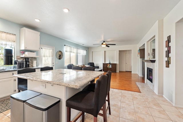 kitchen featuring a breakfast bar, white cabinets, a kitchen island, and light tile patterned flooring