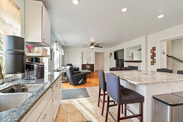 kitchen featuring a kitchen island, white cabinetry, a healthy amount of sunlight, and a breakfast bar