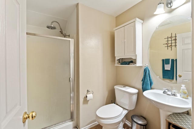 bathroom with a shower with shower door, sink, and toilet