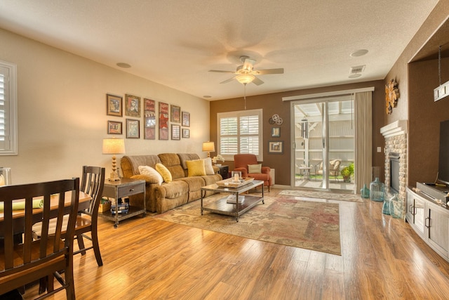 3216 Janine Ave, Rosamond, CA 93560 - living area with a ceiling fan, light wood-style floors, a glass covered fireplace, and a textured ceiling