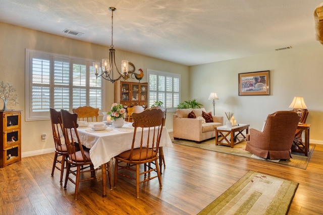 3216 Janine Ave, Rosamond, CA 93560 - dining area featuring a chandelier, wood finished floors, and baseboards