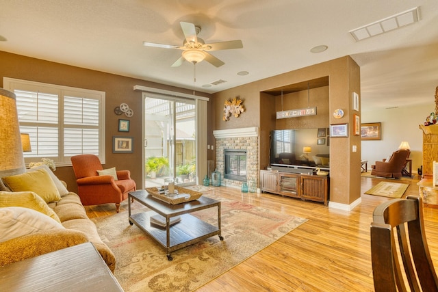 3216 Janine Ave, Rosamond, CA 93560 - living room featuring a brick fireplace, light wood-type flooring, ceiling fan, and baseboards