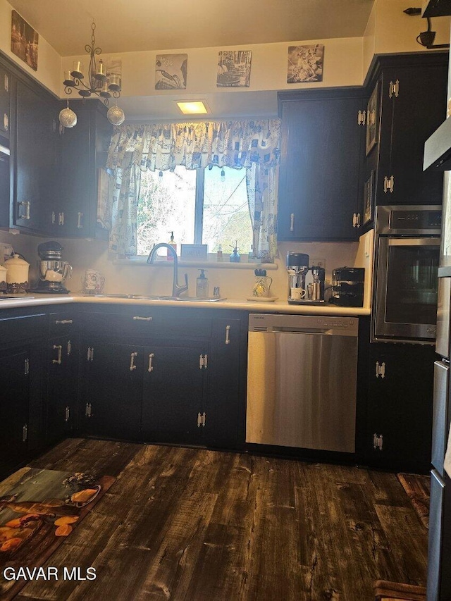 1283 W Lancaster Blvd, Lancaster, CA 93534 - kitchen featuring stainless steel appliances, dark cabinetry, dark wood-type flooring, light countertops, and a chandelier