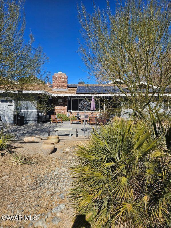 1283 W Lancaster Blvd, Lancaster, CA 93534 - back of house featuring solar panels, a patio, and a chimney