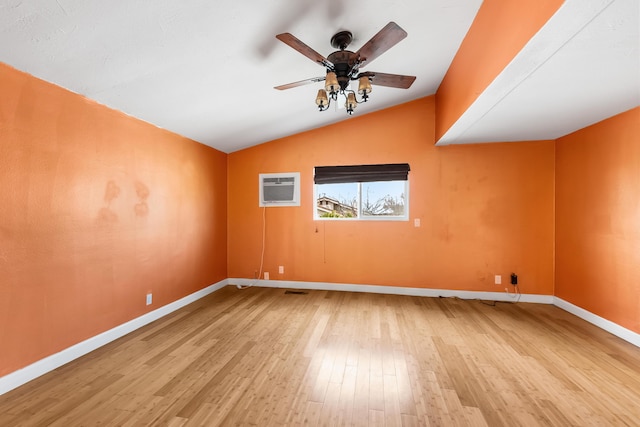 empty room with lofted ceiling, ceiling fan, wood finished floors, baseboards, and a wall mounted AC