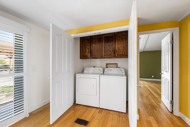 washroom featuring cabinet space, visible vents, light wood-style flooring, separate washer and dryer, and baseboards