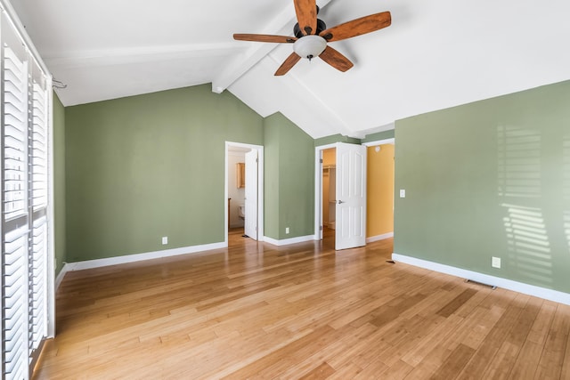 unfurnished bedroom with vaulted ceiling with beams, a spacious closet, ceiling fan, light wood-type flooring, and baseboards