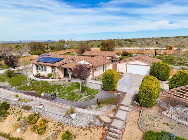 single story home with a garage, roof mounted solar panels, fence, and concrete driveway