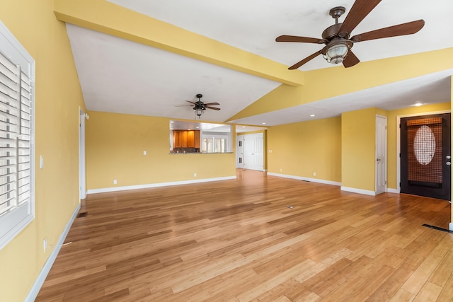 unfurnished living room with light wood-style floors, vaulted ceiling with beams, baseboards, and a ceiling fan