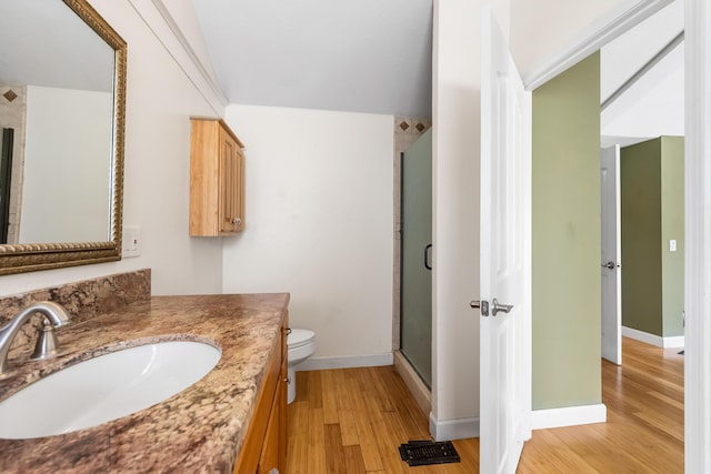 full bathroom with toilet, wood finished floors, vanity, baseboards, and a stall shower