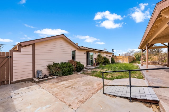 rear view of house with a gate, fence, solar panels, and a patio