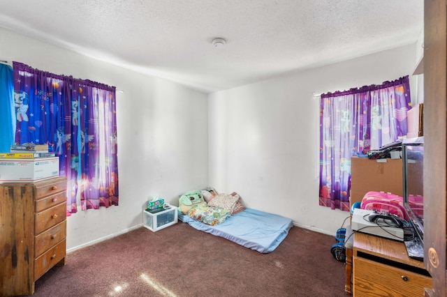 bedroom with dark colored carpet and a textured ceiling