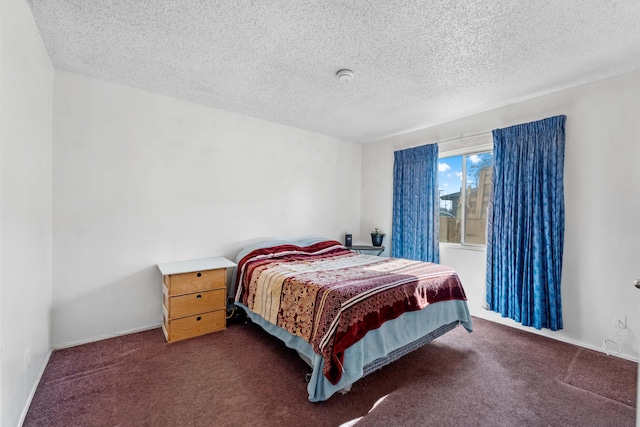 bedroom with a textured ceiling and dark colored carpet