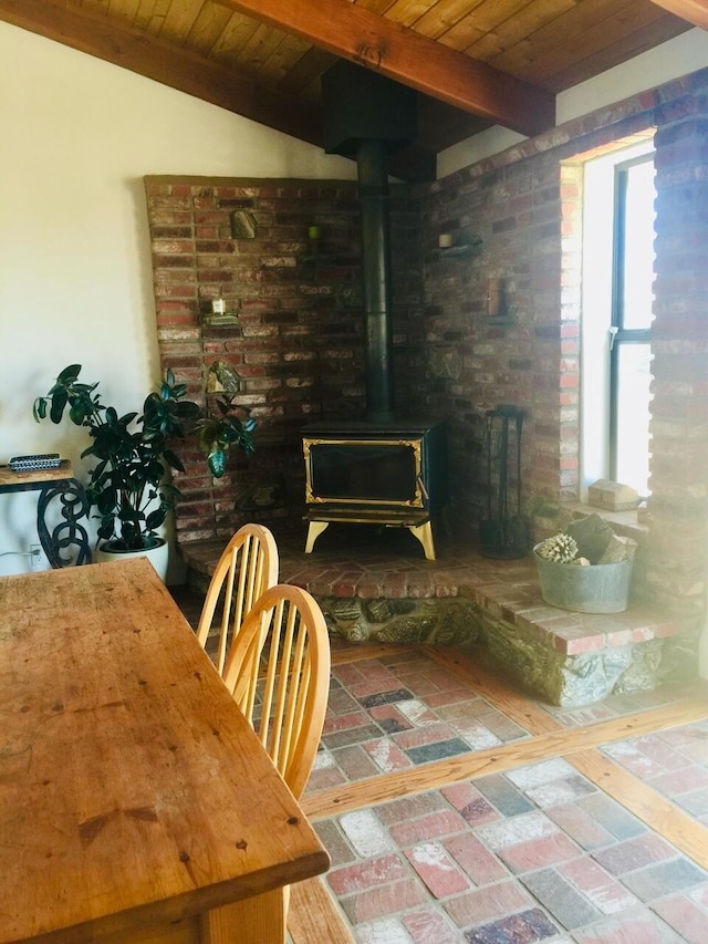 dining room featuring lofted ceiling with beams, a wood stove, and wooden ceiling