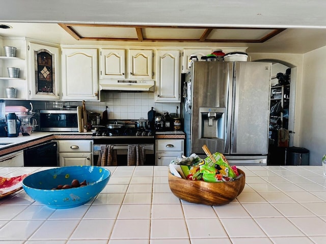 kitchen with tasteful backsplash, tile countertops, cream cabinets, and black appliances