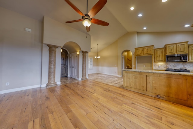 24281 Jacaranda Dr, Tehachapi, CA 93561 - kitchen with arched walkways, light wood-style flooring, stainless steel microwave, decorative columns, and ceiling fan with notable chandelier