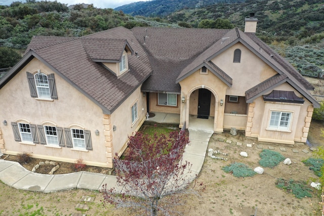 24281 Jacaranda Dr, Tehachapi, CA 93561 - view of front of property with a mountain view, a shingled roof, stucco siding, and a chimney
