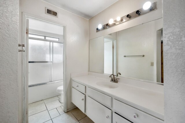 full bathroom featuring vanity, combined bath / shower with glass door, tile patterned floors, and toilet