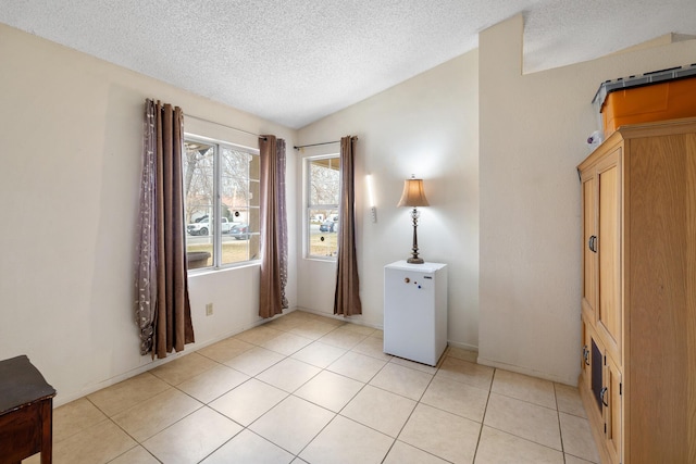 tiled spare room with vaulted ceiling and a textured ceiling