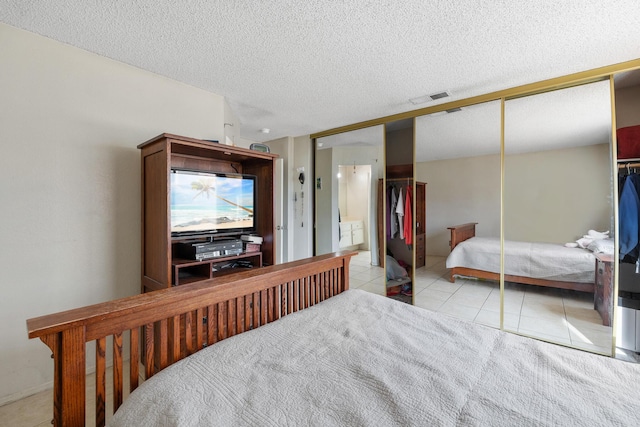 bedroom featuring a closet, a textured ceiling, and light tile patterned floors