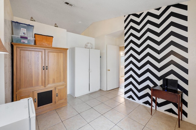 kitchen with lofted ceiling, a textured ceiling, and light tile patterned floors