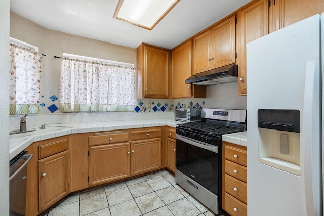 kitchen featuring stainless steel appliances, sink, tile countertops, and light tile patterned floors