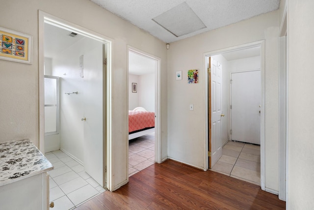 hallway with a textured ceiling and light wood-type flooring