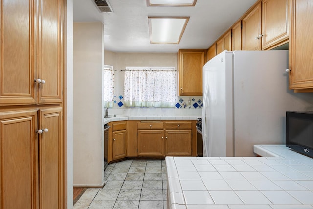 kitchen featuring appliances with stainless steel finishes, tile countertops, light tile patterned floors, and backsplash