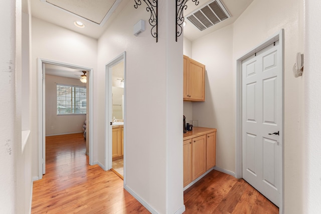 hall featuring light wood-type flooring and an inviting chandelier