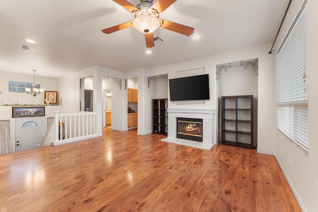 unfurnished living room with hardwood / wood-style floors and ceiling fan with notable chandelier