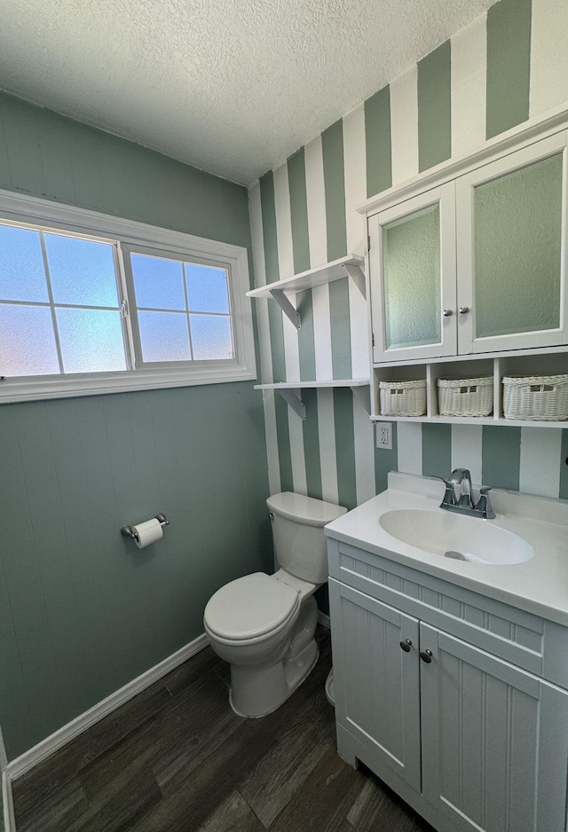 bathroom with hardwood / wood-style floors, vanity, toilet, and a textured ceiling