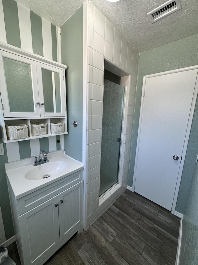 bathroom with hardwood / wood-style floors, vanity, a textured ceiling, and a shower with shower door