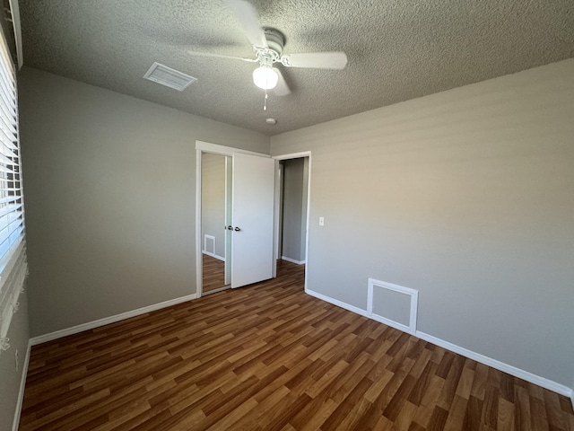 unfurnished bedroom featuring a textured ceiling, ceiling fan, and dark wood-type flooring