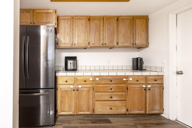 kitchen with dark hardwood / wood-style flooring, tile countertops, and stainless steel refrigerator