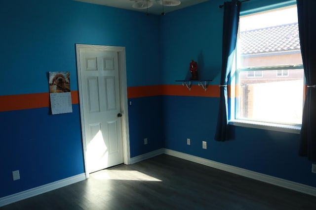 unfurnished room with a ceiling fan, wood finished floors, a healthy amount of sunlight, and baseboards