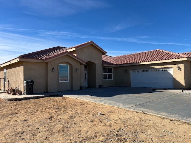 view of front of house with stucco siding, an attached garage, a tile roof, and driveway