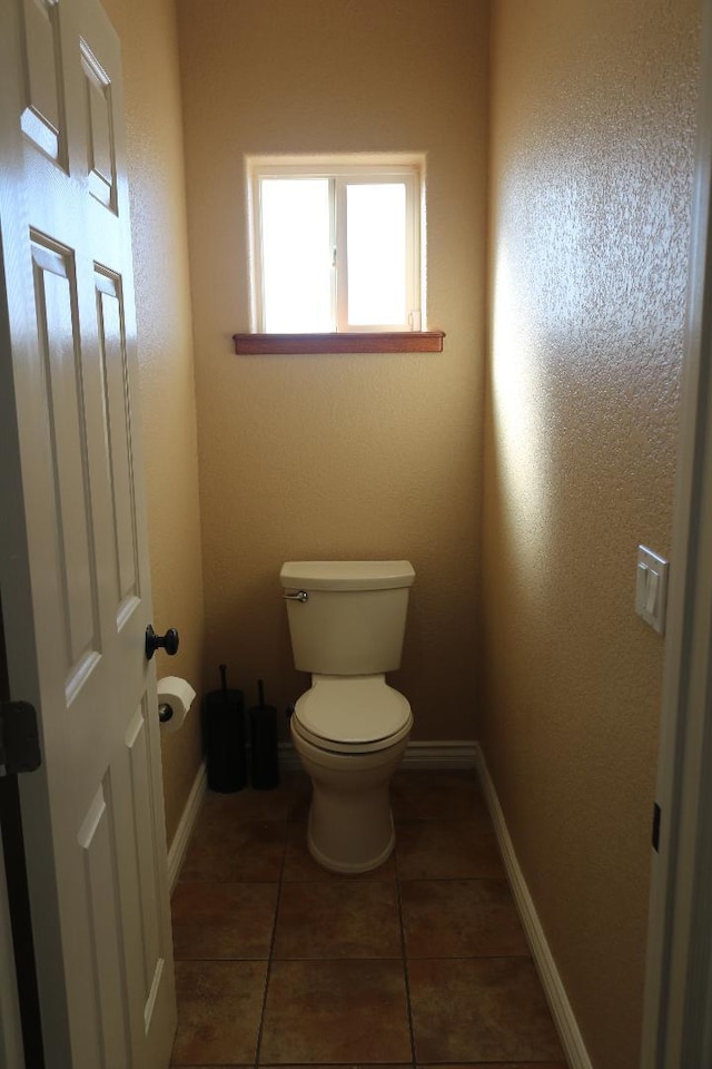 bathroom featuring tile patterned flooring, toilet, and baseboards