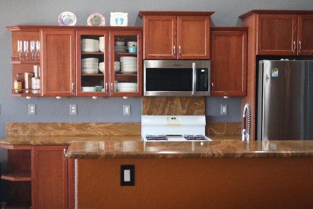 kitchen featuring glass insert cabinets, brown cabinetry, stone countertops, stainless steel appliances, and open shelves