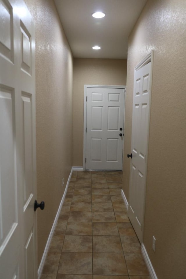 corridor featuring tile patterned floors, recessed lighting, and baseboards