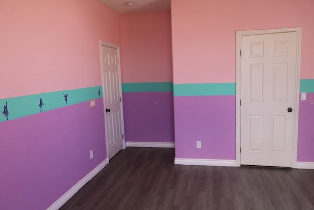 spare room with baseboards and wood finished floors