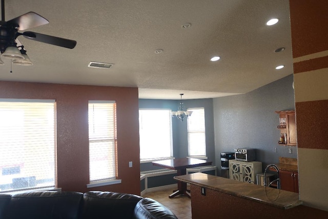 living room featuring visible vents, light tile patterned floors, ceiling fan with notable chandelier, recessed lighting, and a textured ceiling