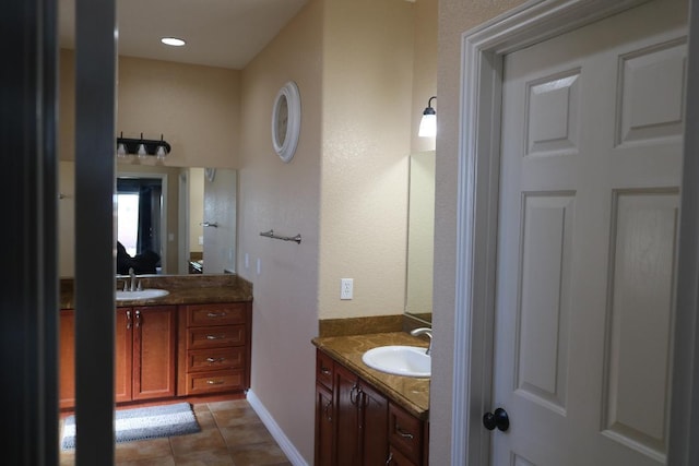 bathroom with a sink, baseboards, two vanities, and tile patterned floors