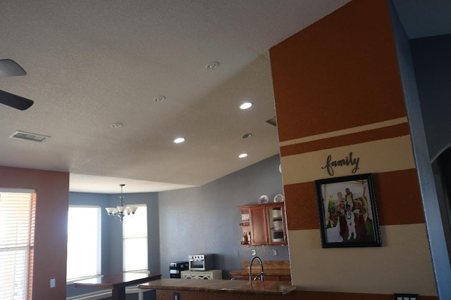 kitchen with visible vents, vaulted ceiling, brown cabinets, recessed lighting, and a notable chandelier