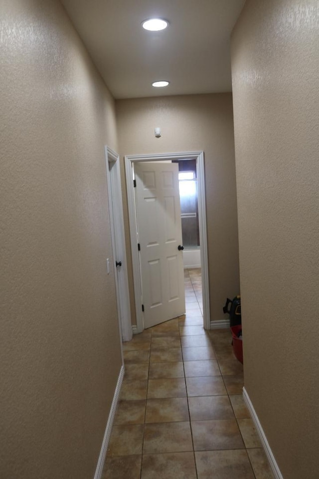 hall featuring tile patterned flooring and baseboards