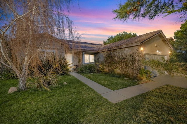 ranch-style home featuring a tile roof, a front lawn, and stucco siding