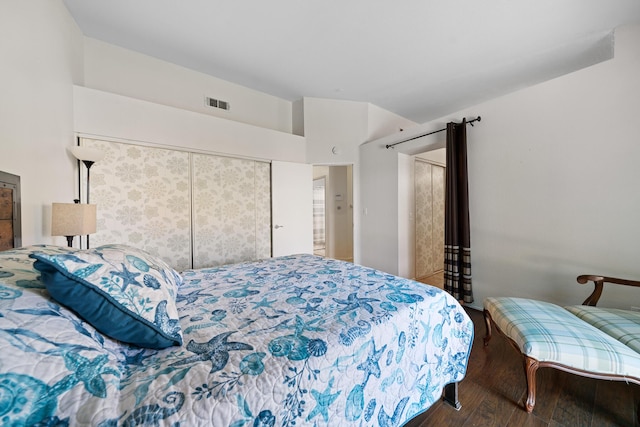 bedroom with vaulted ceiling, a closet, wood finished floors, and visible vents